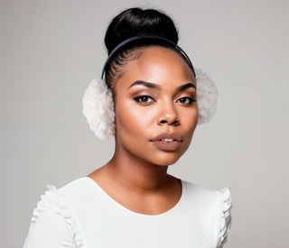 Woman wearing white faux fur earmuffs.