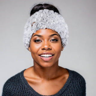 Woman with a bun hairstyle wearing a faux fur satin lined winter headband in white and black.