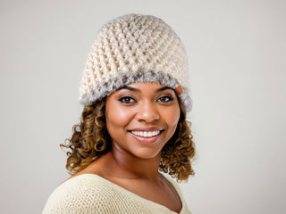 Woman wearing a cream satin lined winter hat with a gray faux fur trim.