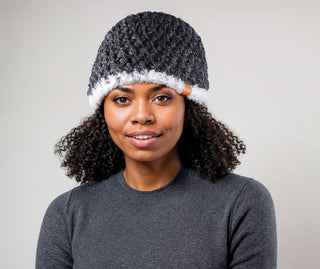 Woman with natural hair wearing a charcoal satin lined winter hat with a white faux fur trim.